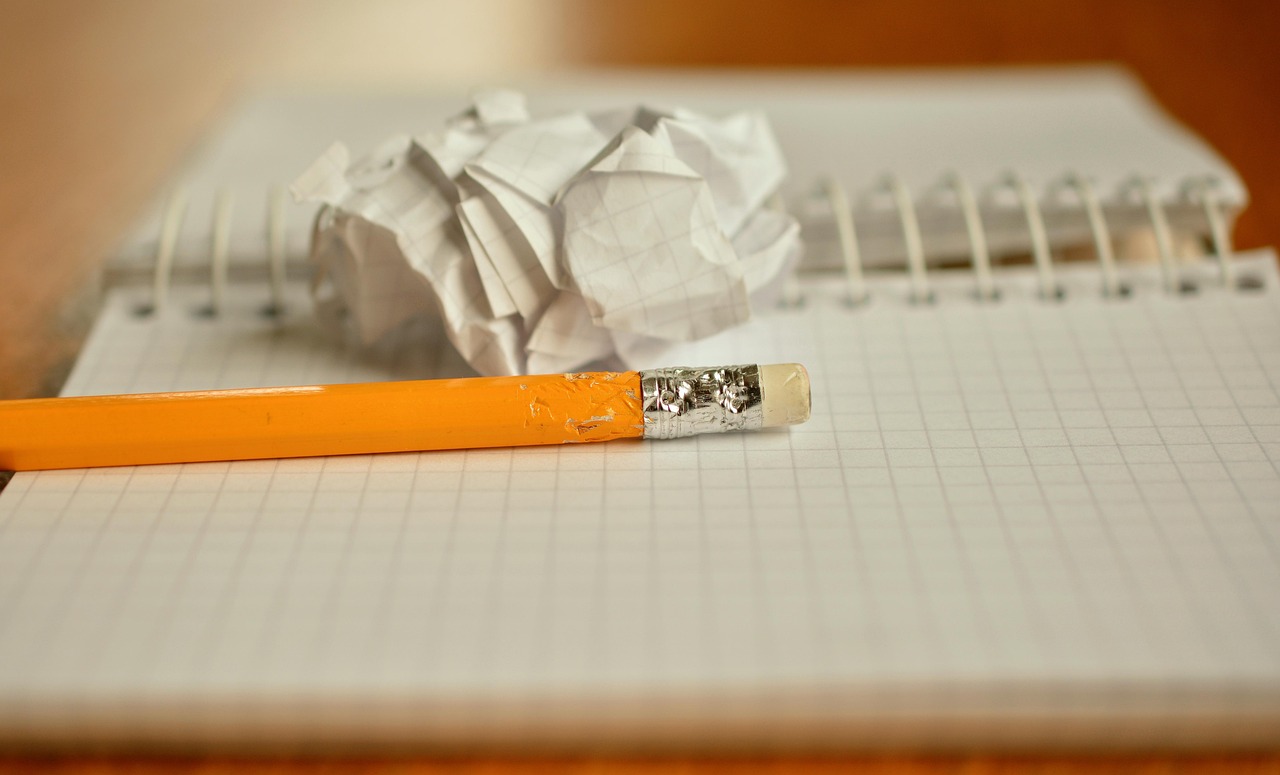 Crumpled sheets of paper piled beside a desk