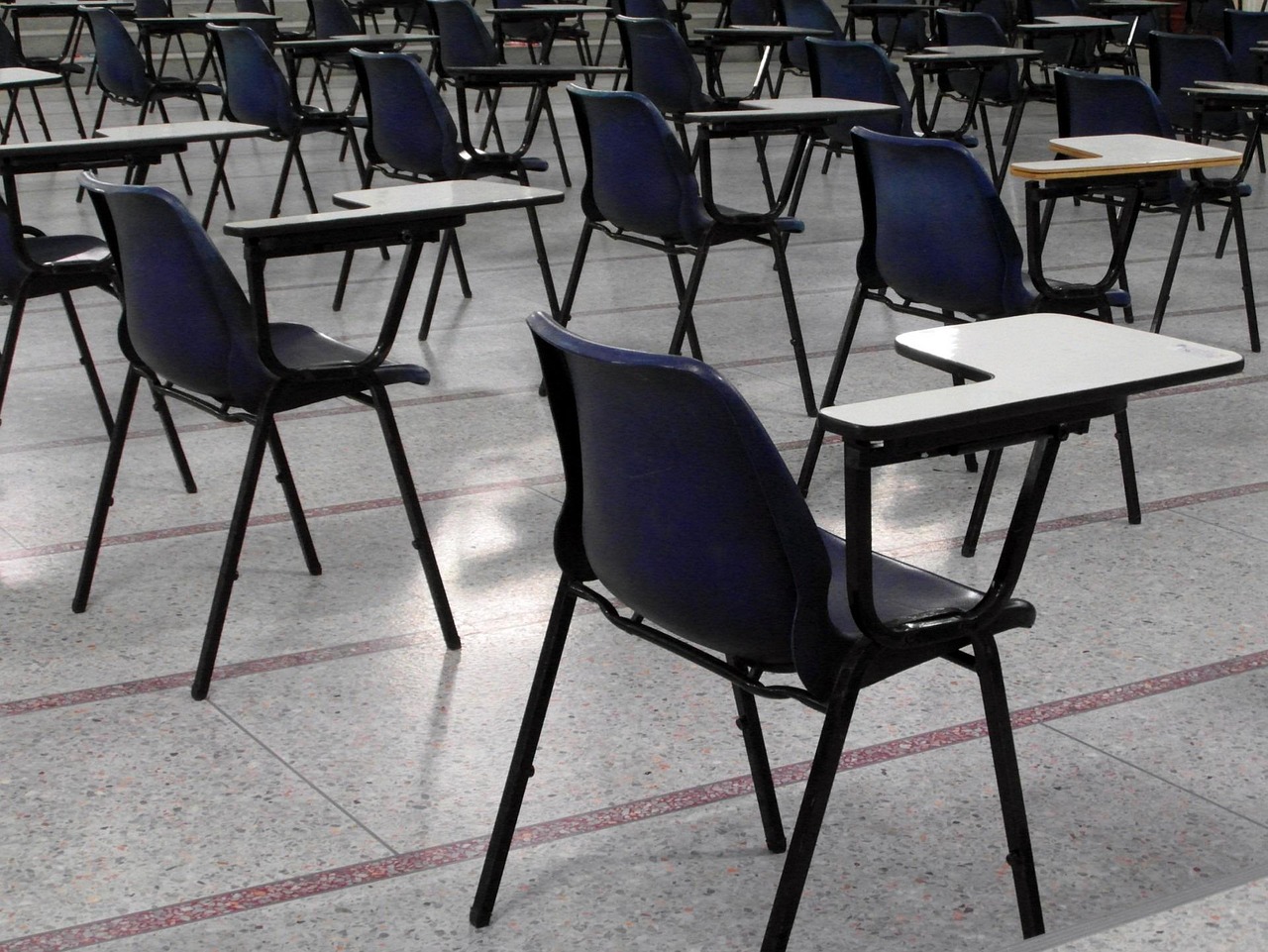 Rows of single desks set out in an empty exam hall