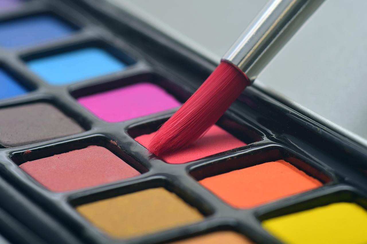 Paintbrushes and a palette of bright colours on a table