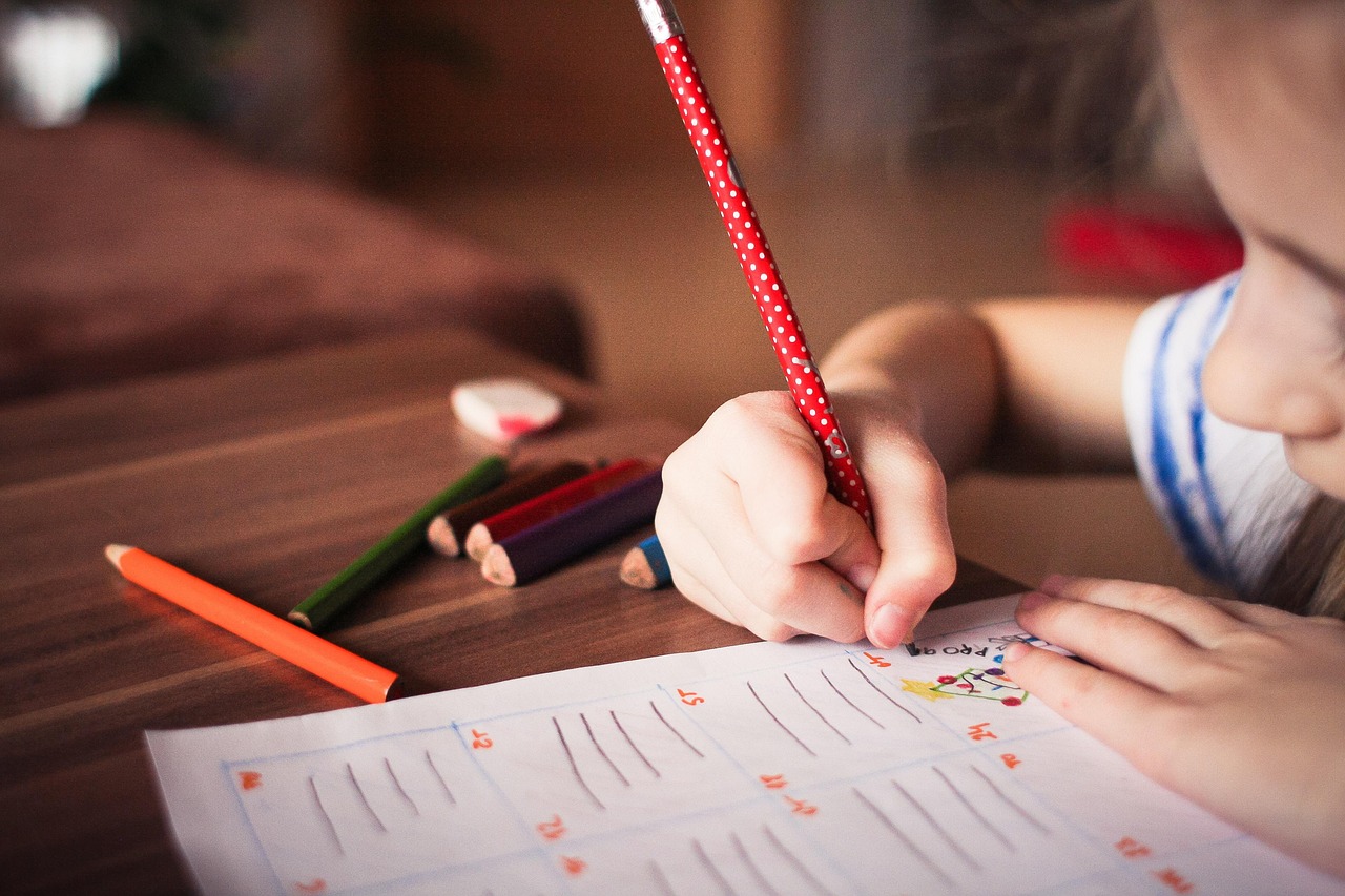 A hand working through maths problems in a notebook.