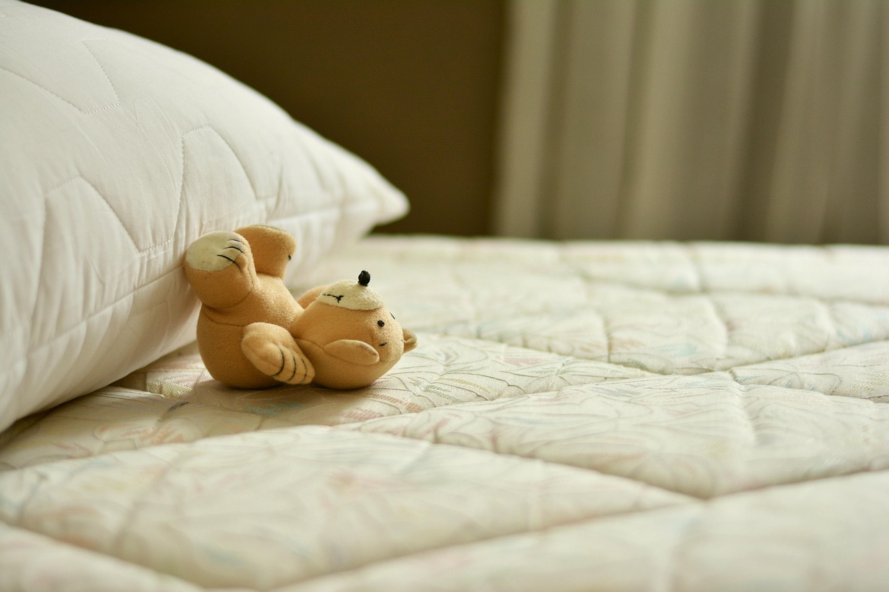 A soft teddy bear on a child's bed